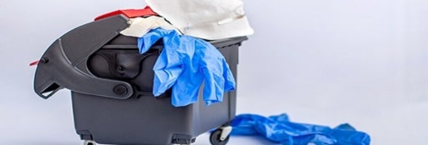 Used protective respiratory mask and medical gloves in the trash can. Coronavirus quarantine is finished on a white background. World coronavirus outbreak. Coronavirus waste pollutes the environment.