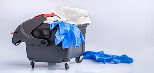 Used protective respiratory mask and medical gloves in the trash can. Coronavirus quarantine is finished on a white background. World coronavirus outbreak. Coronavirus waste pollutes the environment.